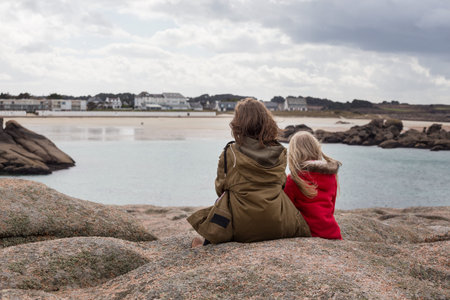 the sisters are sitting on the shore of the ocean  at  the Tregastel, Brittany. France