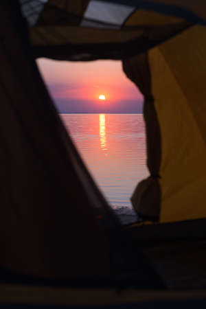happy weekend by the sea - tent on a sunset background and silhouettes of children walking on the sea. Ukrainian landscape at the Sea of Azov, Ukraineの写真素材