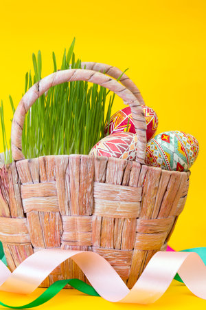 Happy Easter - basket with beautiful Easter egg Pysanka handmade on a yellow background. ukrainian...