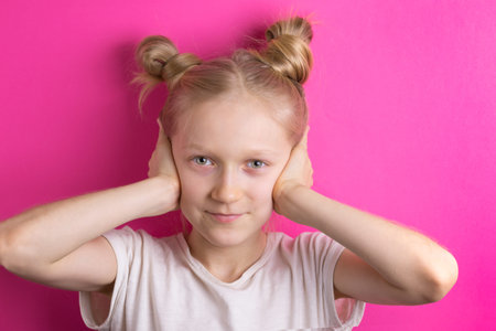 little beautiful girl blonde on a pink background covers her ears with her hands. I do not hear...