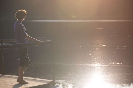 tourist girl on a mountain lake synevyr standing on a pier at sunset. Carpathians,  Ukraine.の写真素材