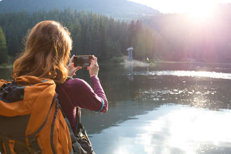 tourist girl making a photo shoot of  mountain lake synevyr. Carpathians,  Ukraine.の写真素材