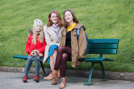 happy mother and daughters  sitting on a bench smiling and looking at the camera, Franceの写真素材