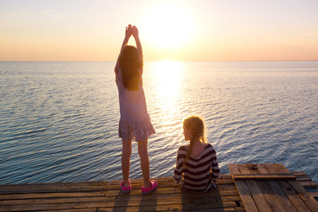 two little girls on the pier at sunset. Ukrainian landscape at the Sea of Azov, Ukraine