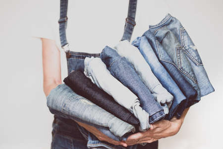The girl holds a stack of jeans in her hands. cleaning in the closet.の写真素材