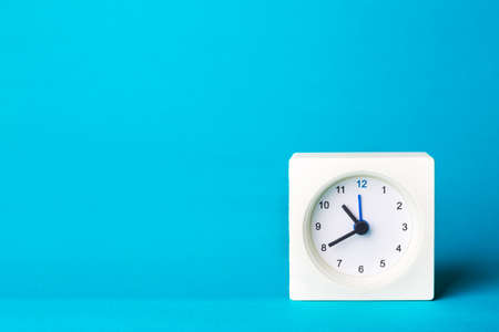 small square white clock on a blue backgroundの写真素材