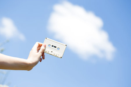 cassette in the hands of the girl against the blue sky. vintage mood