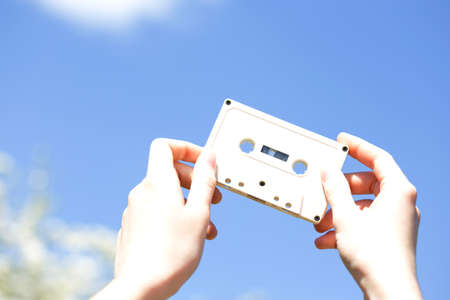 cassette in the hands of the girl against the blue sky. vintage moodの写真素材