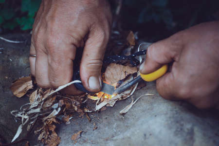 extreme conditions. hike and camping life. tourist man striking fire with the flint and steelの写真素材