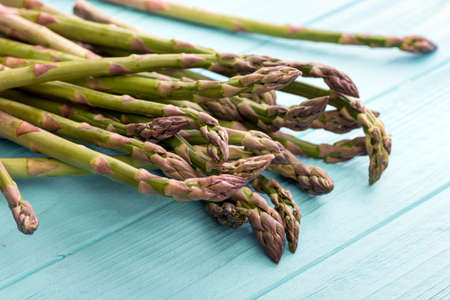 the fresh asparagus on the blue wooden background. veganism and raw foodsの写真素材