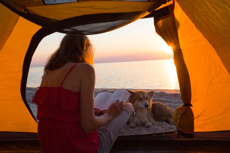 happy weekend by the sea - girl with a dog in a tent on the beach at dawn. Ukrainian landscape at the Sea of Azov, Ukraineの写真素材