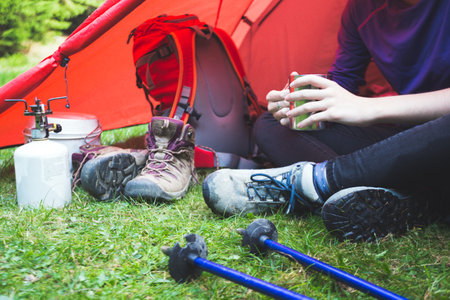 hike and camping life. view of the tent and resting tourist girl with a cupのeditorial素材