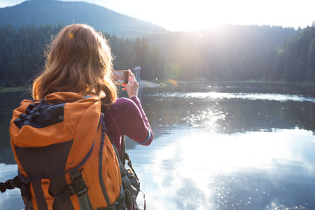 tourist girl making a photo shoot of  mountain lake synevyr. beautiful landscape. Carpathians,  Ukraine.のeditorial素材