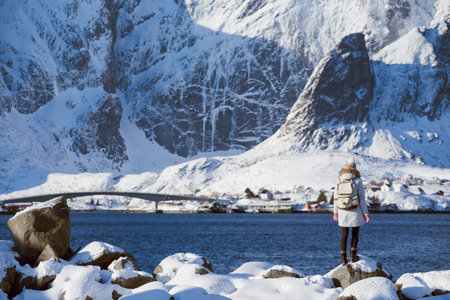 winter, girl walks along the shore of the fjord. Lofoten islands, Norway