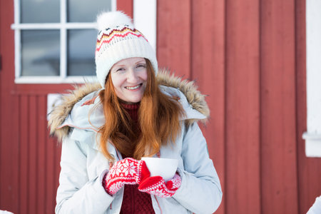 winter. girl with a cup on the background of rorbu on the Lofoten islands. Norwayの写真素材