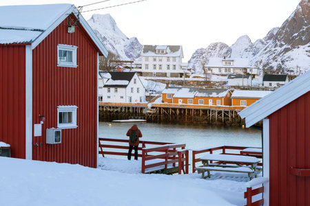 traditional norwegian wooden house rorbu to stand on the shore of the fjord and mountains in the distance. Lofoten Islands. Norway.のeditorial素材