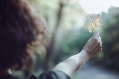 autumn mood - fun happy girl holds a yellow leaf. focus on the sheet