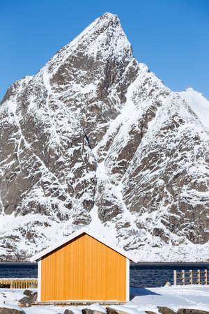 traditional norwegian wooden house rorbu to stand on the shore of the fjord and mountains in the distance. Lofoten Islands. Norway. world travelの写真素材