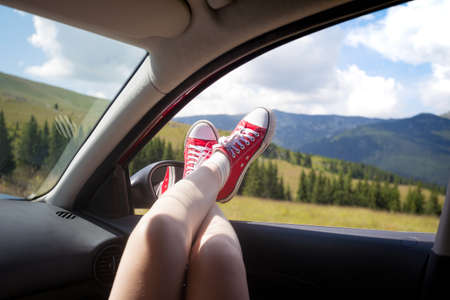 Girl legs in bright sneakers sticking out of the carの写真素材