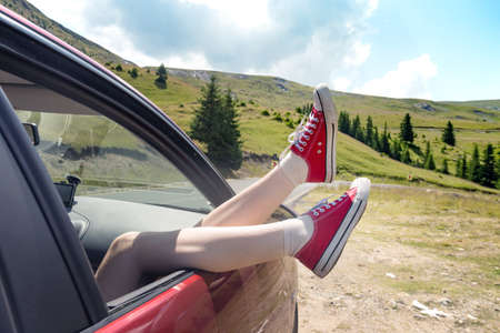 Girl legs in bright sneakers sticking out of the carの写真素材