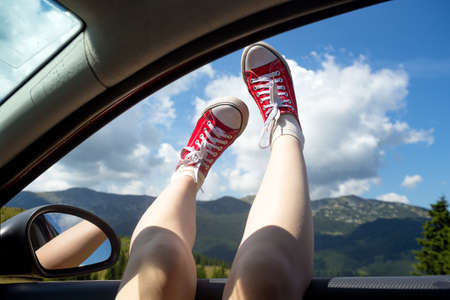 Girl legs in bright sneakers sticking out of the carの写真素材