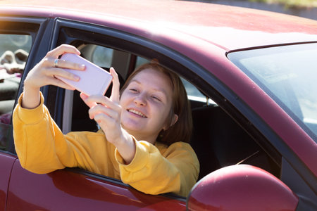 Summer Road Trip. Happy girl takes a selfie while sitting in a car