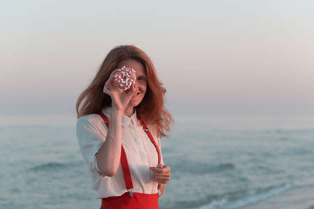 happy smiling girl with a donut on the seashore. birthday celebrationの写真素材