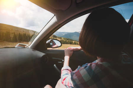 Summer Road Trip. Happy beautiful girl traveling in a car across  at the mountains. Romaniaの写真素材