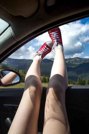Girl legs in bright sneakers sticking out of the car