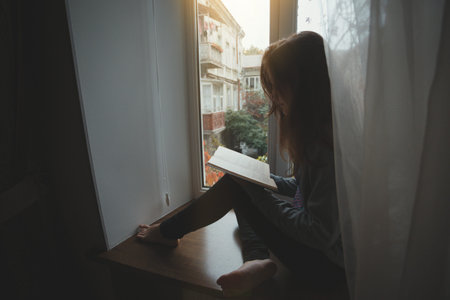 teen girl sitting on a windowsill with a book  in the childrens room