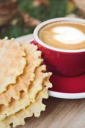 red cup of coffee against the backdrop of autumn foliage with waffles. fall and relax