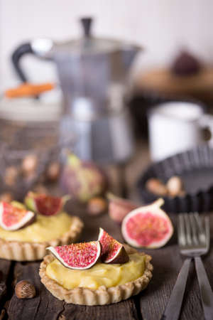 tasty tartlets with custard cream and figs on wooden backgroundの写真素材
