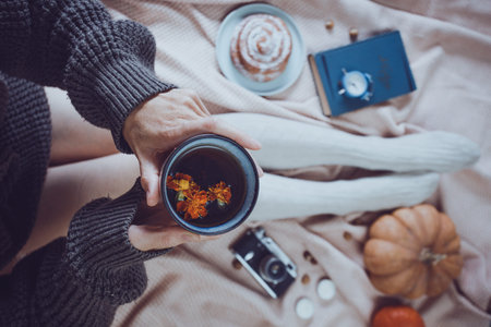 atmospheric autumn background. girl holds cup of tea. bun, pumpkin, apples, book, headphones, retro camera in frameの写真素材