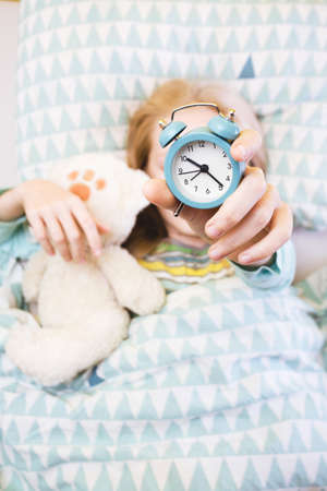 alarm clock disturbing a sleeping little girl that is defocusedの写真素材