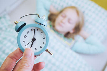 alarm clock disturbing a sleeping little girl that is defocusedの写真素材