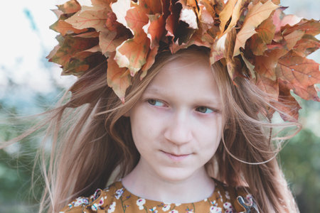 fun young girl at the park with diadem from yellow maple leaves