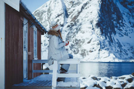 winter. girl with a cup on the background of rorbu on the Lofoten islands. Norwayの写真素材