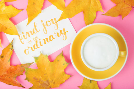 beautiful coffee yellow cup  cappuccino on pink background and maple leaves near  with the...