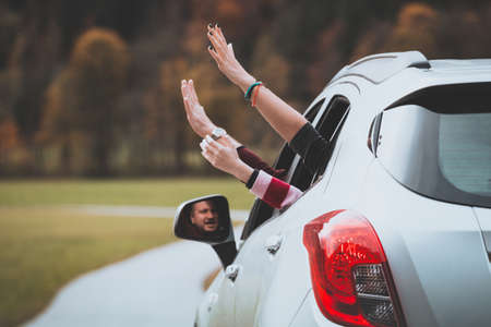 hands of men and girl peering out of a car window on a background of mountains. Summer Road Trip.の写真素材