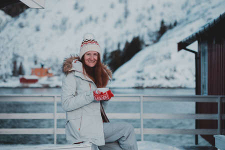winter. girl with a cup on the background of rorbu on the Lofoten islands. Norwayの写真素材