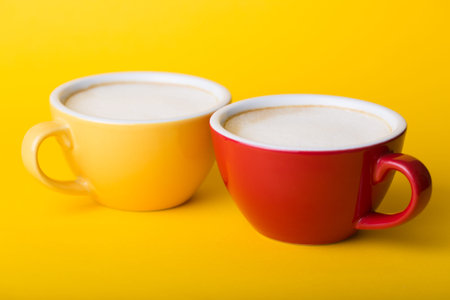 beautiful coffee yellow and red cup with cappuccino on yellow backgroundの写真素材