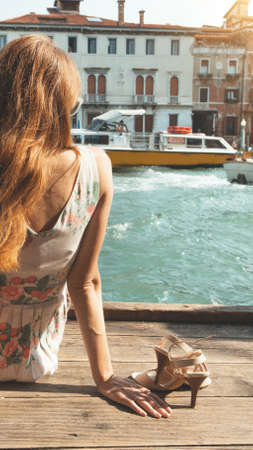 girl sitting on a pier near the canal in venice. Italyの写真素材