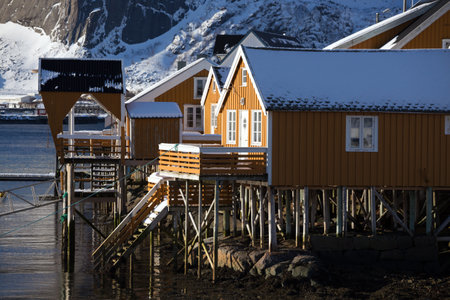 traditional norwegian wooden house rorbu to stand on the shore of the fjord and mountains in the distance. Lofoten Islands. Norway.のeditorial素材
