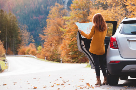 travel by car. Road trip -  tourist girl with a map is standing near the car. Austria