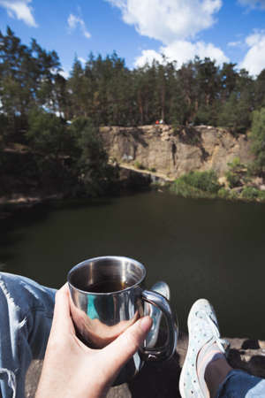 girl hiker sitting by the lake and  holding a cupの写真素材