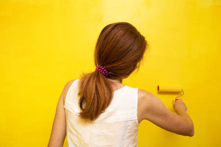 Interior Design. Girl paints a wall in yellow
の写真素材