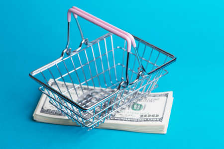Prices for shopping consumer basket products. empty basket on a blue background full of dollarsの写真素材