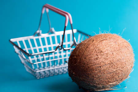 big coconut on a blue background. tropical fruit and shopping consumer basketの写真素材