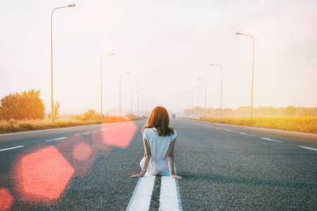 problems in the journey. the girl is sitting on the dividing strip on the road.
の写真素材