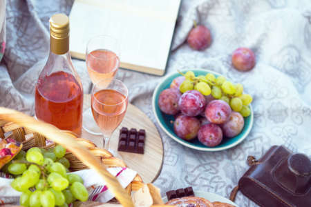 Summer - picnic in the meadow.  baguette, wine, glasses, grapes and rolls in a basket on green grassの写真素材